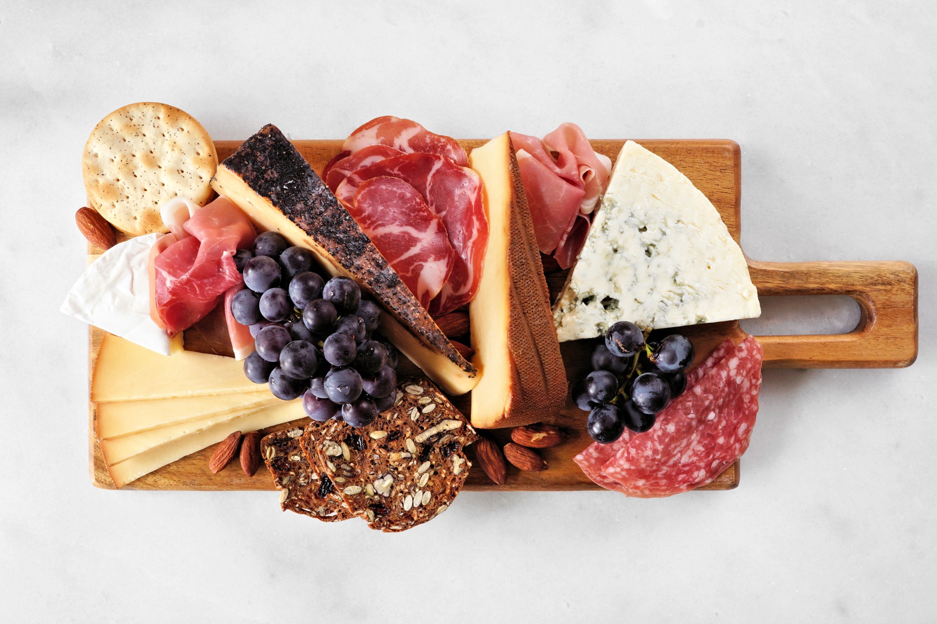 Charcuterie board top view on a white marble background