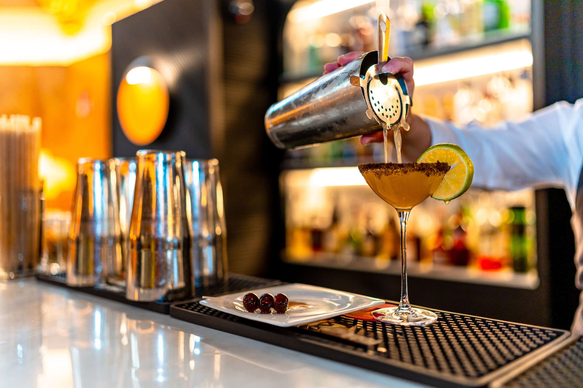 Waiter pouring cocktail into martini glass in a night club